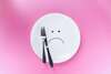 Visage triste sur assiette symbolisant contrôle alimentaire difficile