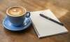 Carnet ouvert et tasse de café, illustrant un temps de réflexion et d'intégration lors d'un changement de vie.
