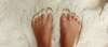 Pieds nus dans le sable illustrant l'ancrage somatique et le retour au corps pour apaiser le système nerveux.