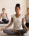 Femme en tenue sport pratiquant étirement yin yoga plage
