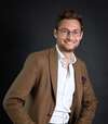 Jeune homme souriant en costume clair sur fond noir