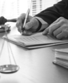 Personne en robe d'avocat signe document avec balance justice