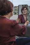 femme se regardant dans un miroir avec une coiffure en cours de transformation