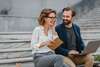 homme-femme-seduisants-assis-dans-escaliers-du-centre-ville-urbain-travaillant-ensemble-ordinateur-portable