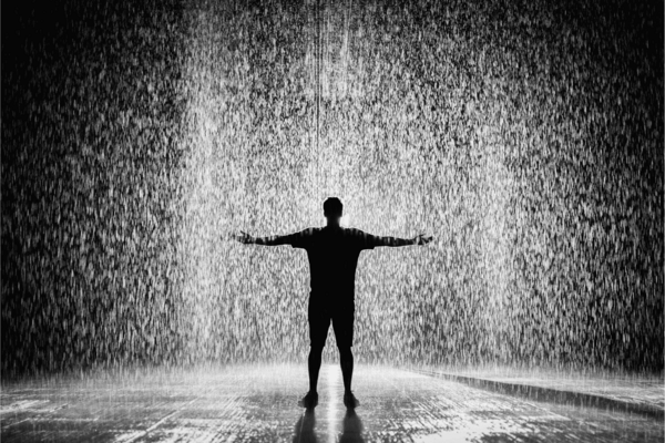 Silhouette d'une personne accueillant la pluie à bras ouverts, symbolisant la récupération gratuite de l'eau de pluie. Cette image illustre l'importance de la collecte de l'eau de pluie pour un usage durable et écologique sans coût supplémentaire.