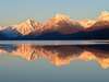 Montagnes enneigées reflétées dans un lac calme au lever du soleil