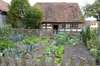 Jardin potager soigné avec légumes en rangées et maison ancienne