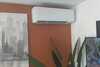 Climatiseur Mitsubishi gris clair fixé proprement sur mur blanc