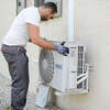 Technicien installant un système de cylindre sécurisé sur mur extérieur de maison