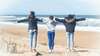 trois personnes les bras écartés sur la plage