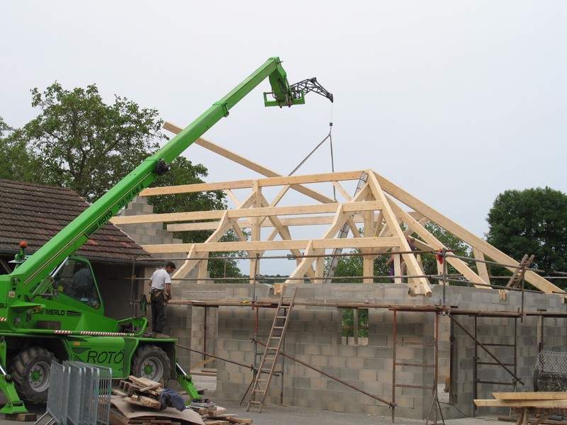 Charpente à trois pans en sapin traité et lamellé-collé pour une cantine scolaire.