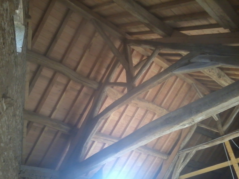 Vue de dessous de la charpente de l'écurie en vieux bois de chêne et douglas.