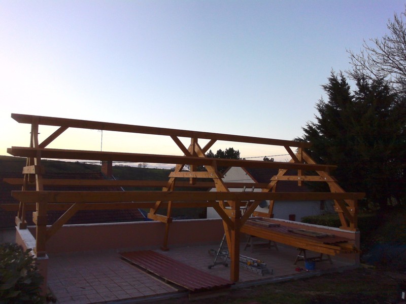 Auvent composé de trois fermes posées sur une terrasse.