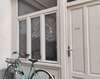 Vélo turquoise stationné devant façade bois blanc Paris