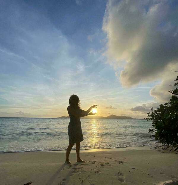 Séverine sur une plage au soleil couchant entourant le soleil de ses mains pour récupérer son énergie