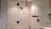 Douche moderne aux parois transparentes dans une salle de bain rénovée avec matériaux durables