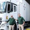 2 LP drivers in front of the cab of a truck docked to transport works of art