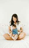 Femme en blanc avec bébé sur genoux en post partum