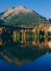 lac d altitude aux eaux claires entouré d arbres aux couleurs automnales avec une grande structure en bois en montagne illustrant la quête de sens