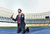 Homme en costume dans un stade à genoux les poings de la victoire lever