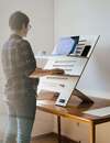 Personne utilisant un rehausseur de bureau pour travail ergonomique