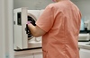 Assistante plaçant des instruments dans l'autoclave de stérilisation