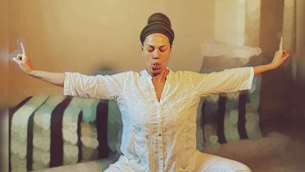 Nathaly Nam Prem Kaur en méditation Kundalini Yoga, bras tendus sur les côtés, souffle Sitali, langue roulée, méditation pour vaincre la colère intérieure.